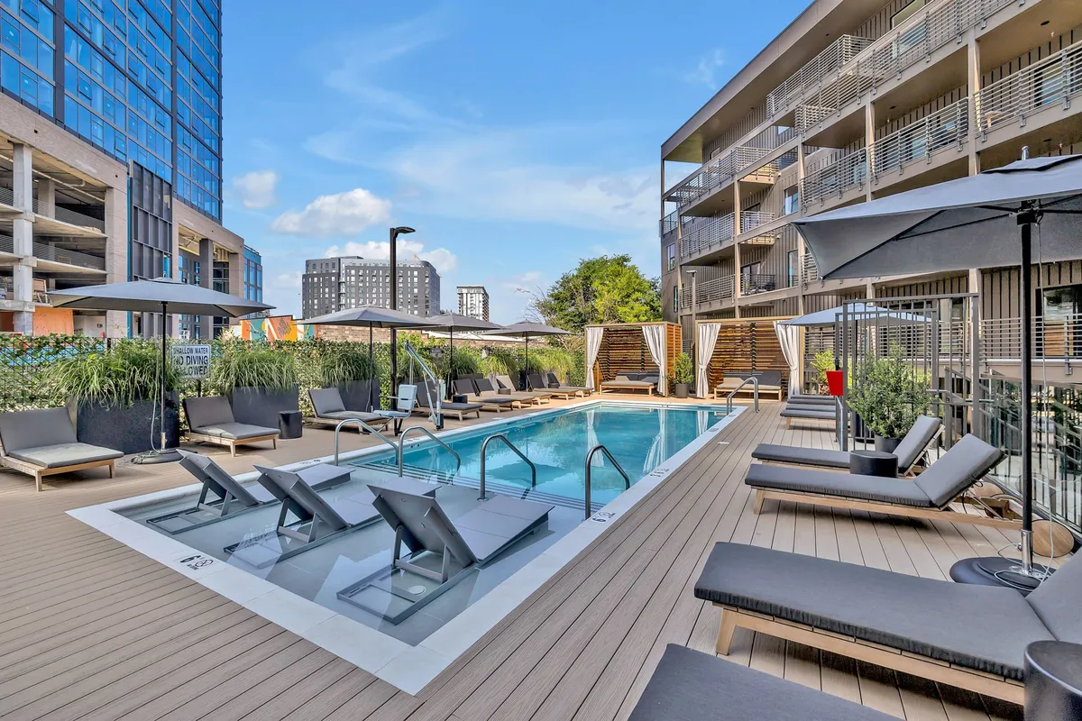 An inviting swimming pool area featuring lounge chairs, umbrellas, and lush landscaping. The setting is perfect for families seeking fun in the sun, with plenty of space to swim, relax, and socialize during the warmer months.