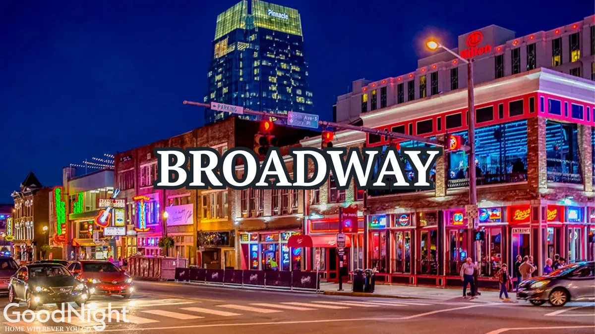 A lively Nashville city street at night, illuminated by neon signs and bustling with people walking between buildings, capturing the city's energetic nightlife scene.